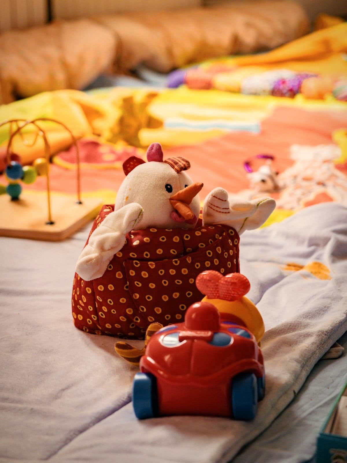 Un doudou et une petite voiture posés sur le tapis d’éveil du salon.