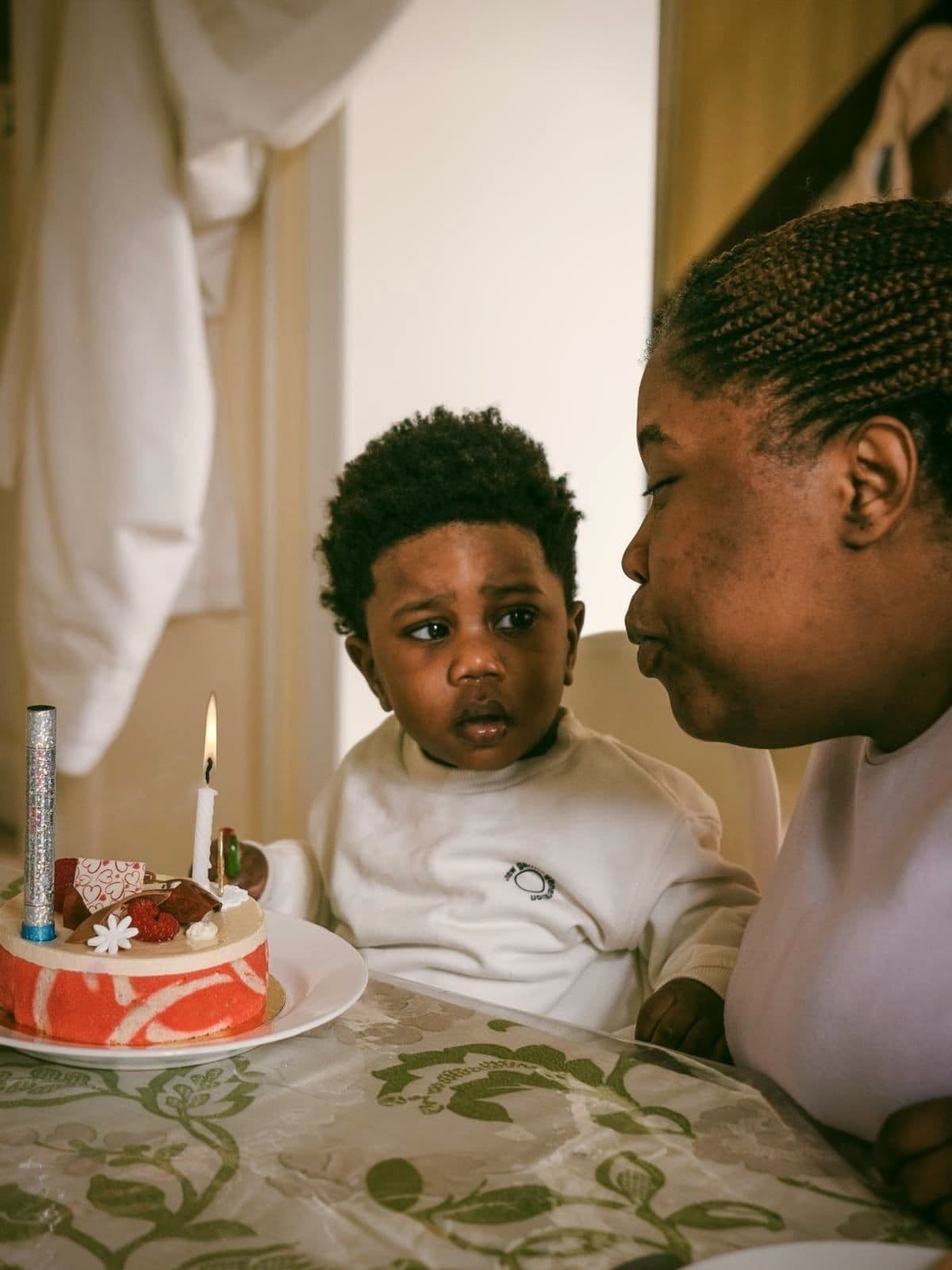 Une maman souffle la bougie du gâteau d’anniversaire de son fils, assis à côté d’elle.